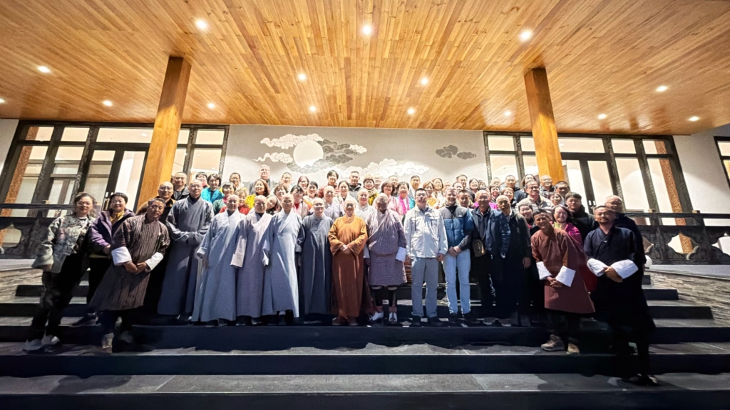 Large farewell group photo of the entire travel group together with Dasho Passang Dorji and the Bhutanese guides on the illuminated steps of the hotel.