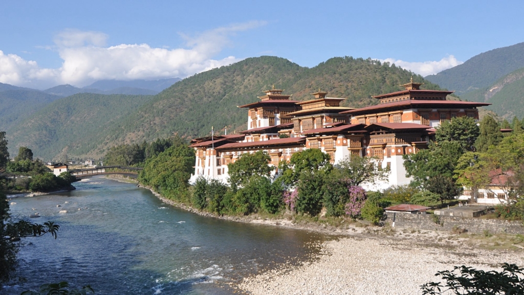 The majestic Punakha Dzong (Palace of Great Happiness) sits picturesquely at the confluence of the Mo Chhu and Pho Chhu rivers against a green mountain backdrop.