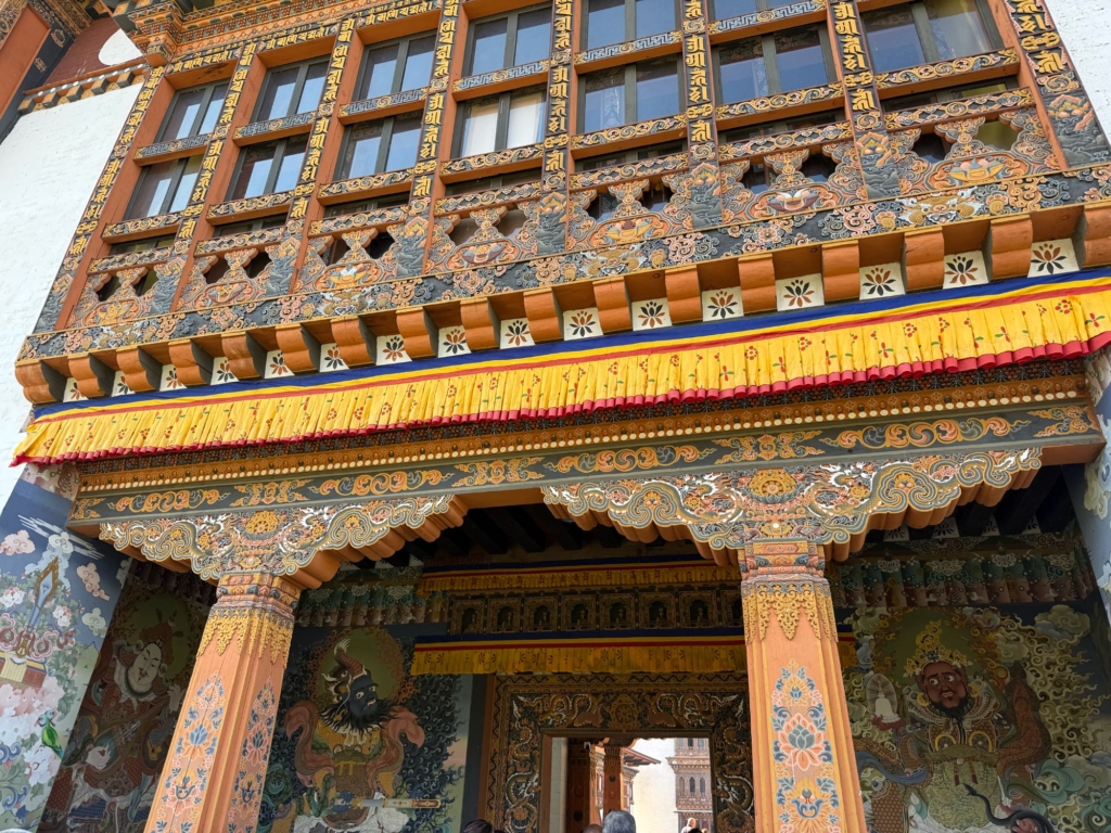 Detailed view of the magnificent, colorful wood carvings and traditional decorations above the main entrance of Wangdue Phodrang Dzong.